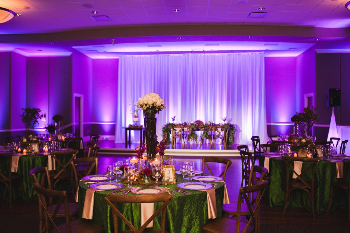View of Grand Ballroom Tables and Stage Decorated and Lit in Purple